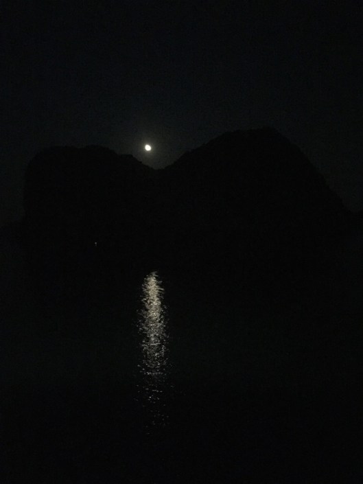Moonrise over a limestone karst cliff in Ha Long Bay.